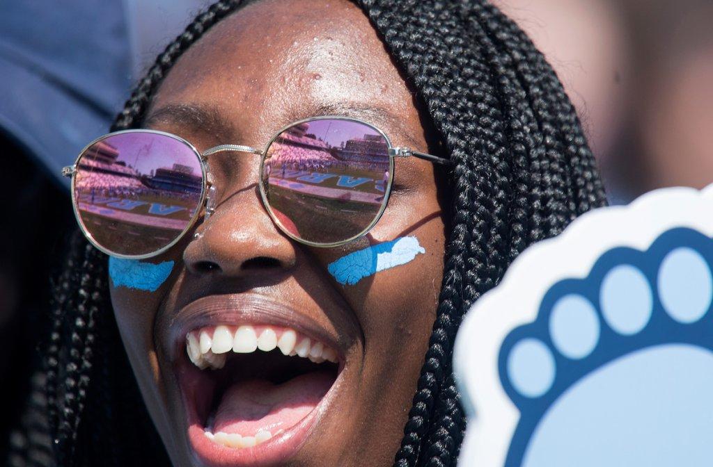 A black female student holding a Tar Heel-shaped foam finger cheers on the U.N.C. 足球队.