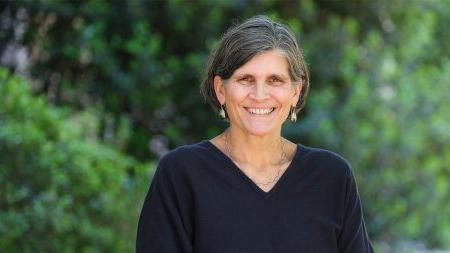 Jill Hamm in front of greenery wearing earrings and a black shirt.